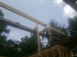 Carpenter setting a ridge beam over a new addition frame — Ice Dam Removal by Roofing Brothers in Normalville