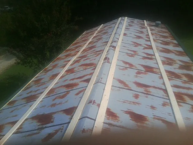 Rusted metal roof panels with new wood purlins before replacement — Storm Damage Roof Repair in Normalville by Roofing Brothers