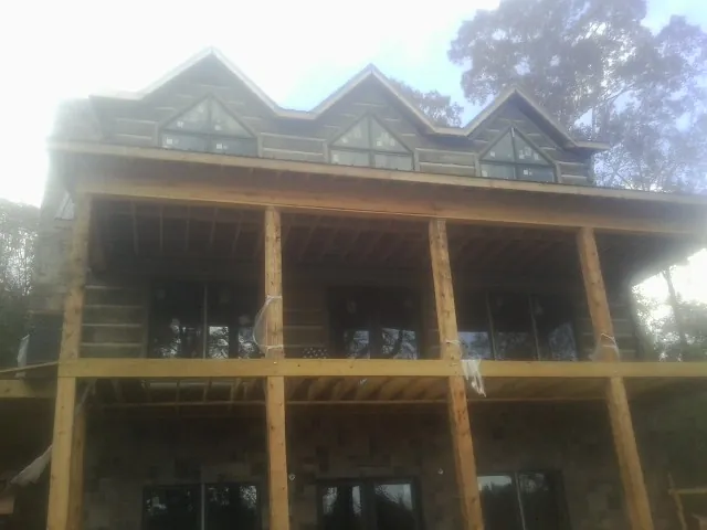 Dormers and porch framing on a large log home under construction — Roof Coating work by our crew in Normalville