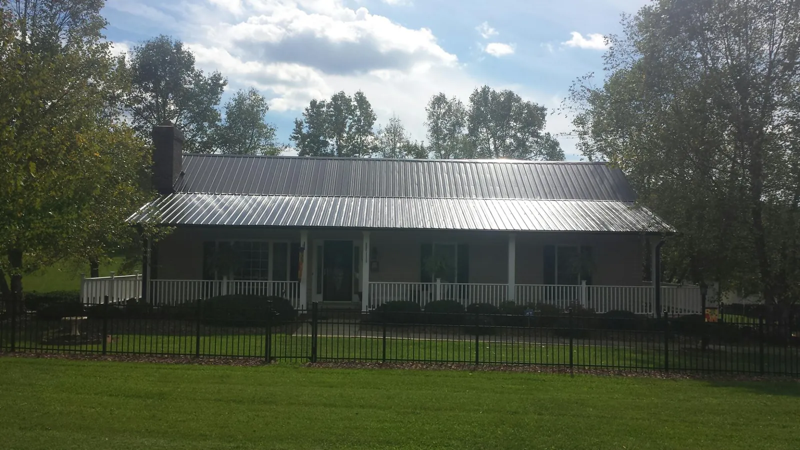 Gray metal roof on a brick ranch with a full width front porch — Gutter Guard Installation work by our crew in Normalville
