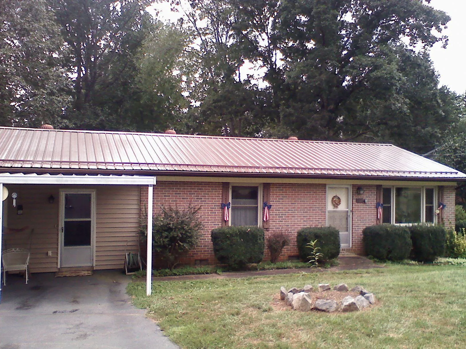 Bronze metal roof and carport on a brick ranch home — Roof Repair work by our crew in Normalville